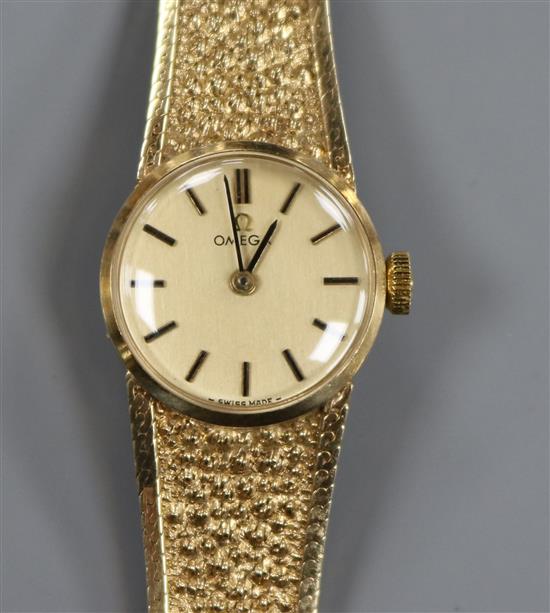 A ladys 9ct gold Omega manual wind wrist watch, on textured 9ct gold Omega bracelet.